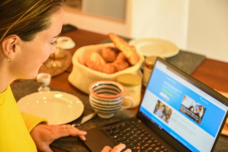 Frau guckt sich am Frühstückstisch auf einem Laptop die Plattform localgutscheining.de an