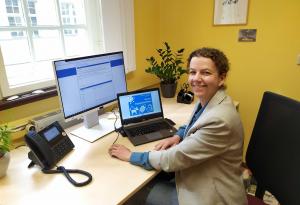 Eine Frau sitzt an einem Arbeitsplatz und hat auf dem Schreibtisch einen Laptop mit dem geöffneten Engagementfinder stehen.