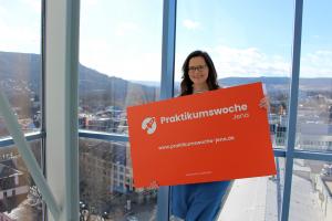 Projektleiterin Daniela Drilltzsch von JenaWirtschaft präsentiert die Werbetafel zur Praktikumswoche 2022.