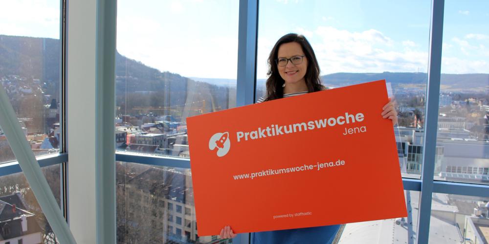 Projektleiterin Daniela Drilltzsch von JenaWirtschaft präsentiert die Werbetafel zur Praktikumswoche 2022.