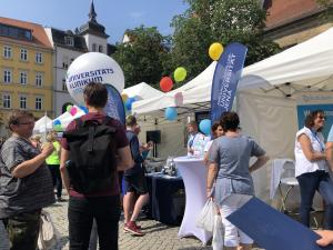 Personen stehen vor Messeständen und unterhalten sich