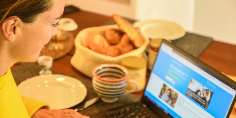 Frau guckt sich am Frühstückstisch auf einem Laptop die Plattform localgutscheining.de an