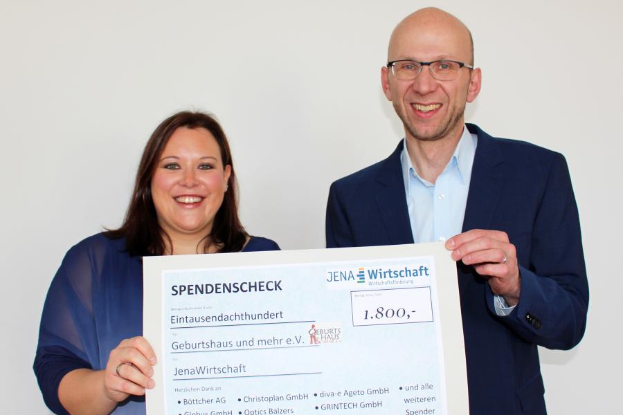 2 Personen präsentieren einen Spendenscheck.