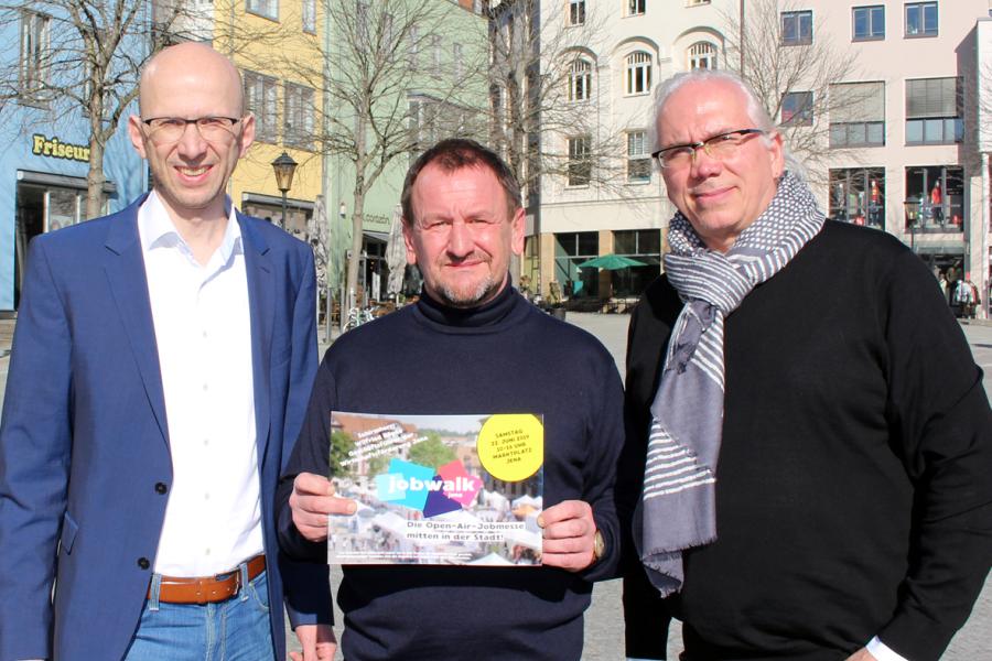 Drei Personen präsentieren eine Broschüre
