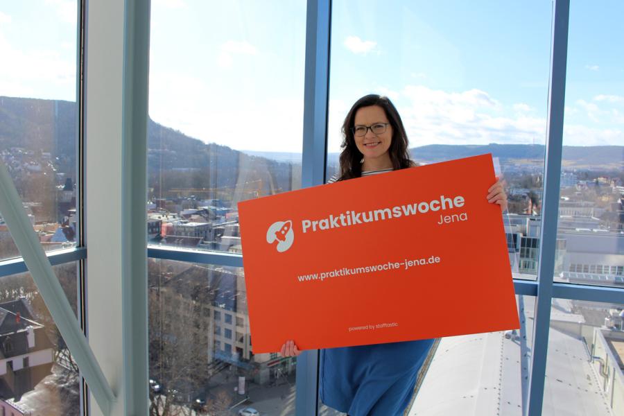 Projektleiterin Daniela Drilltzsch von JenaWirtschaft präsentiert die Werbetafel zur Praktikumswoche 2022.