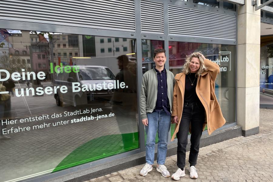 Ein Mann und eine Frau stehen vor der Schaufensterscheibe der neuen Räumlichkeiten des StadtLab Jenas.